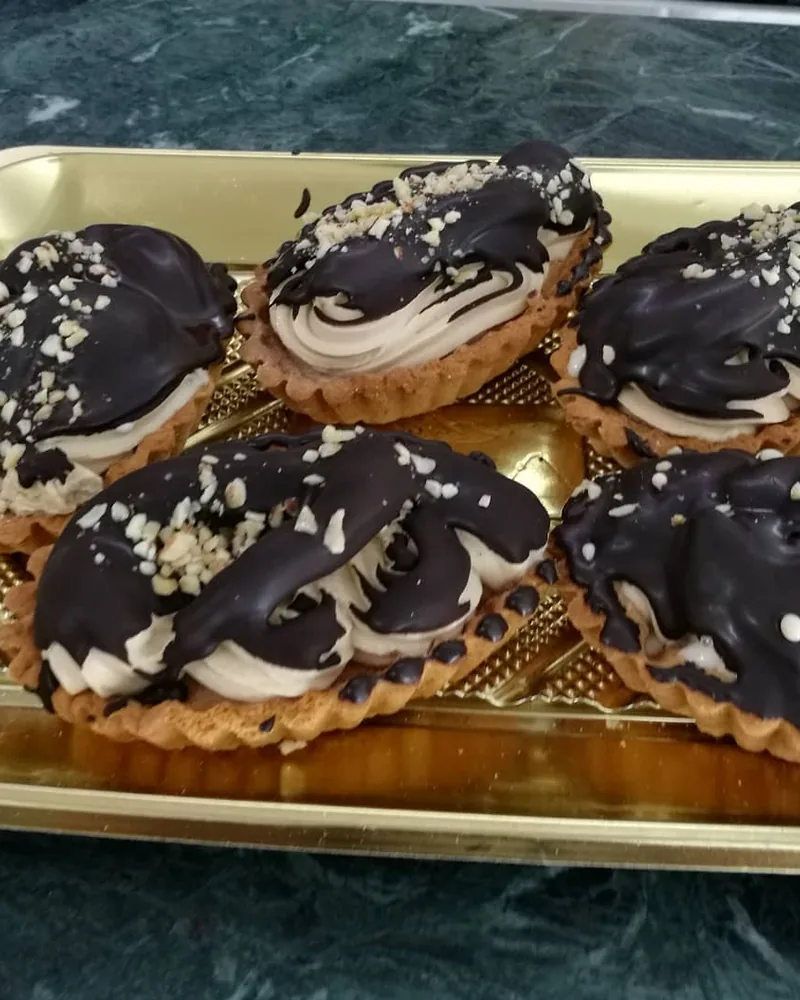 Tartellette ricoperte di cioccolato fondente su vassoio dorato