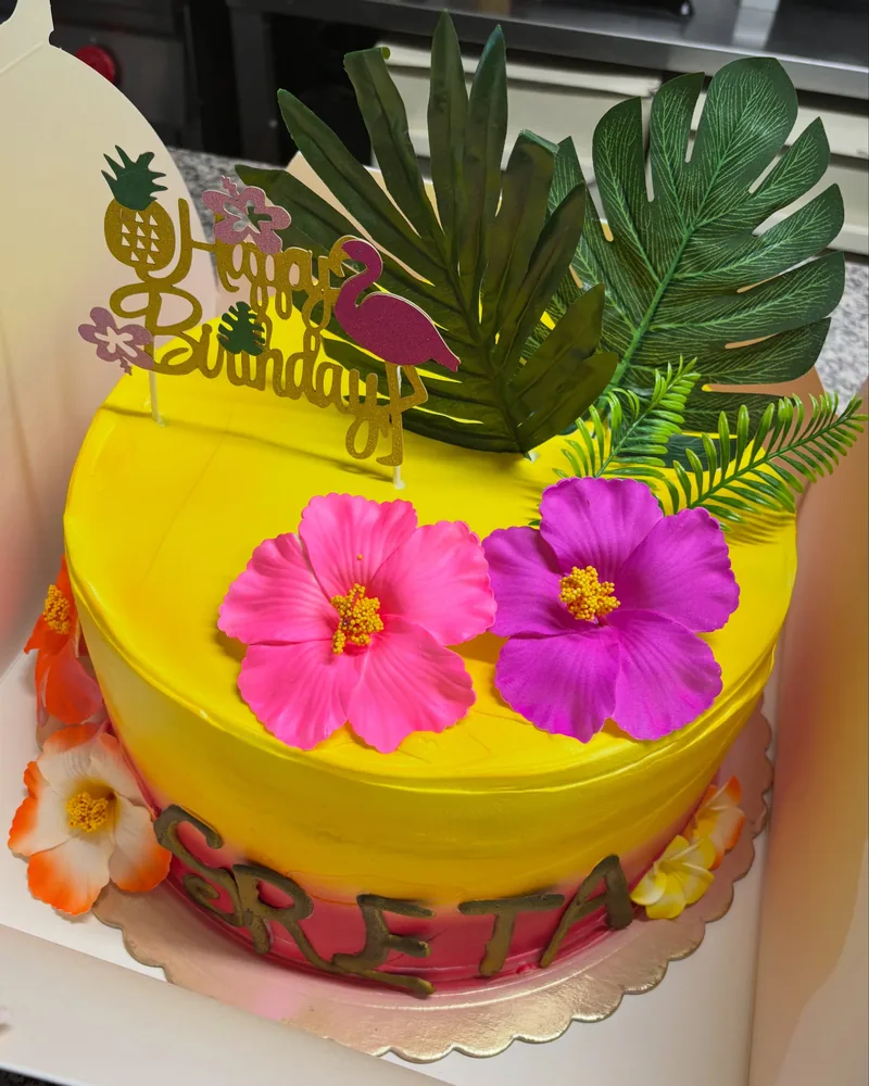 Torta gialla con fiori tropicali e nome in pasta di zucchero